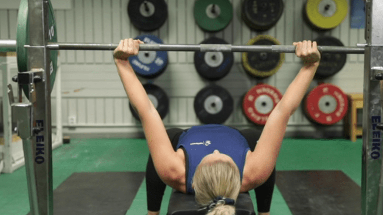 Kvinna utför bänkpress i gym